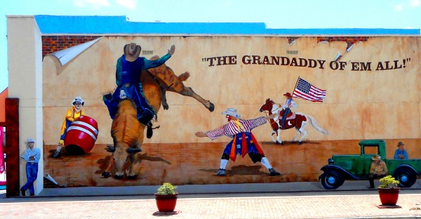 Mural on wall of building in Arcadia, Florida that shows cowboy riding bucking bronco and other rodeo themes including a rodeo clown.